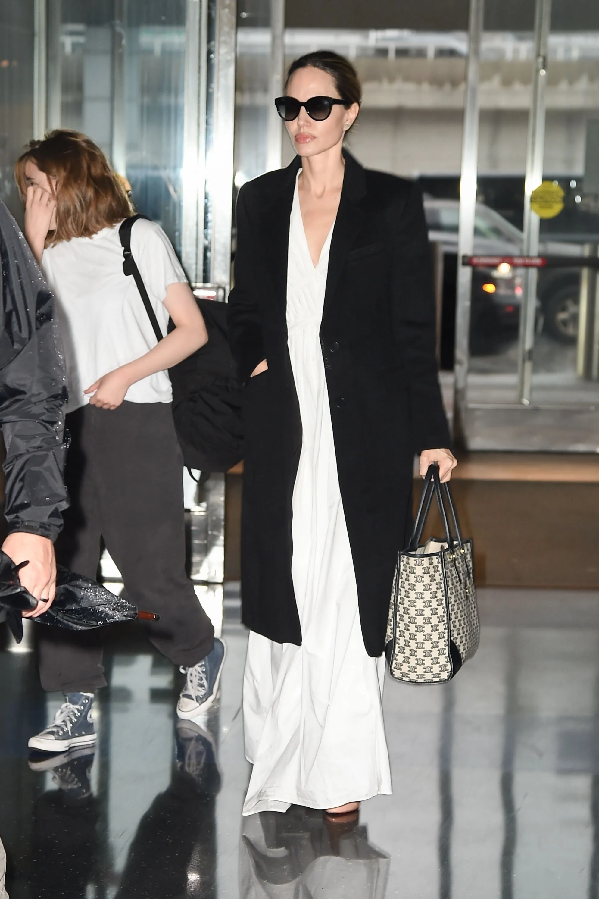 ニューヨーク NY 限定女優アンジェリーナ・ジョリーは、白いロングドレスと黒のトレンチコートを着てエレガントに見えます...